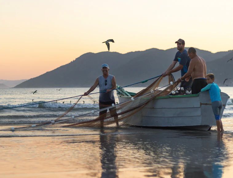 pescadores em um barco jogando uma rede de pesca